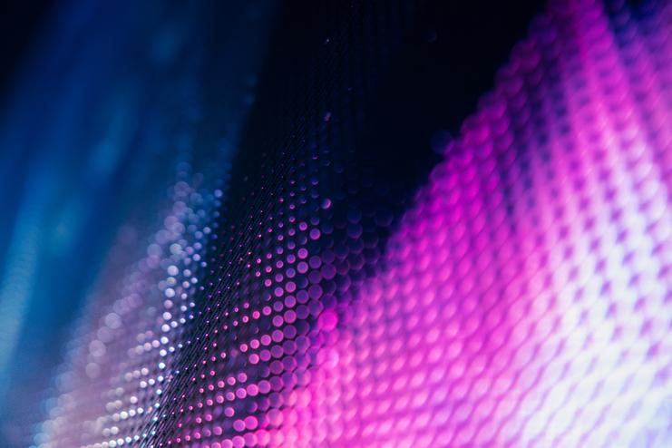 Abstrakte Nahaufnahme mit lila und blauen Lichtpunkten Eine abstrakte, unscharfe Nahaufnahme zeigt lila und blaue Lichtpunkte auf einer strukturierten Oberfläche, die ein futuristisches, digitales oder technologisches Gefühl vermittelt.