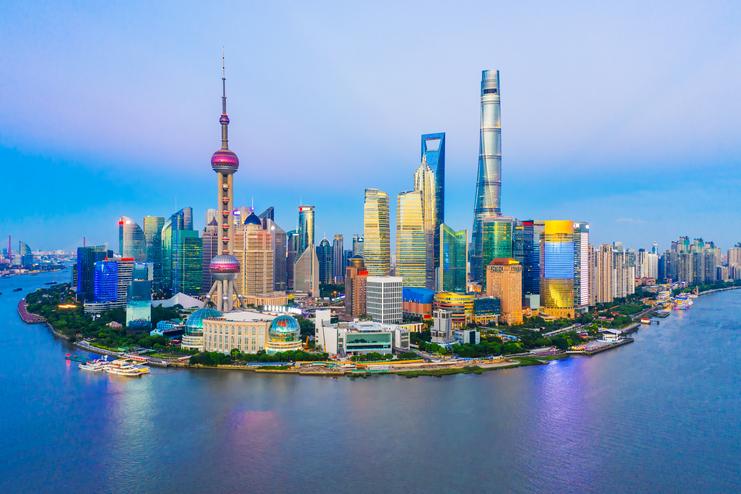 Skyline von Shanghai bei Sonnenuntergang Die moderne Skyline von Shanghai zeigt ikonische Wolkenkratzer wie den Oriental Pearl Tower und Shanghai Tower, beleuchtet bei Sonnenuntergang, mit dem Huangpu-Fluss im Vordergrund.