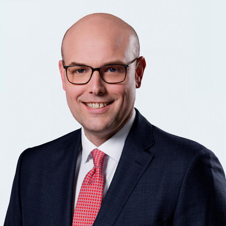 Porträt von Matthias Kleffner, LL.M. Matthias Kleffner, LL.M., ein Mann mit Brille und Glatze, trägt einen dunklen Anzug, ein weißes Hemd und eine rote Krawatte. Er lächelt freundlich in die Kamera vor einem hellen Hintergrund.